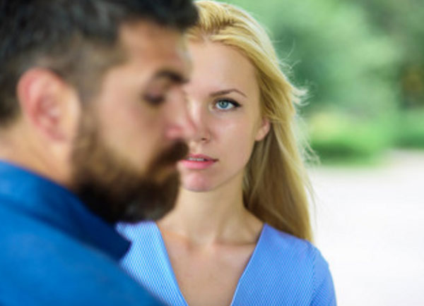 Парень стоит боком, за ним девушка