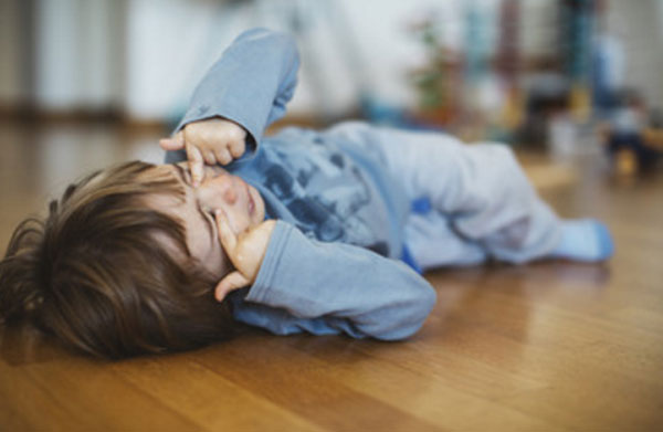 Мальчик лежит на полу и плачет