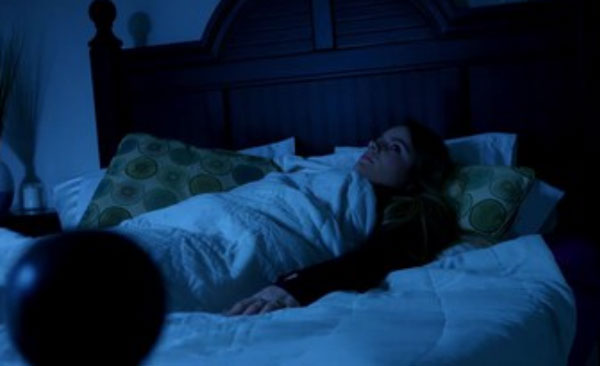 Женщина лежит с открытыми глазами в темной комнате