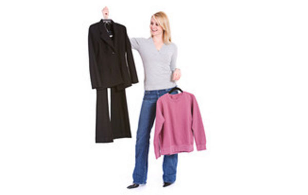 Женщина в одной руке держит вешалку с костюмом, в другой - вешалку со свитером