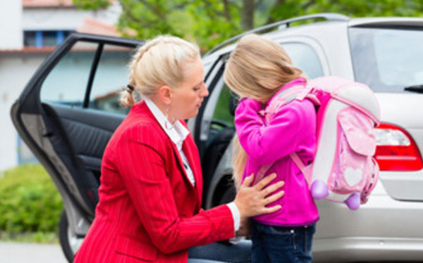 Девочка с рюкзаком на плечах плачет, мама ее успокаивает