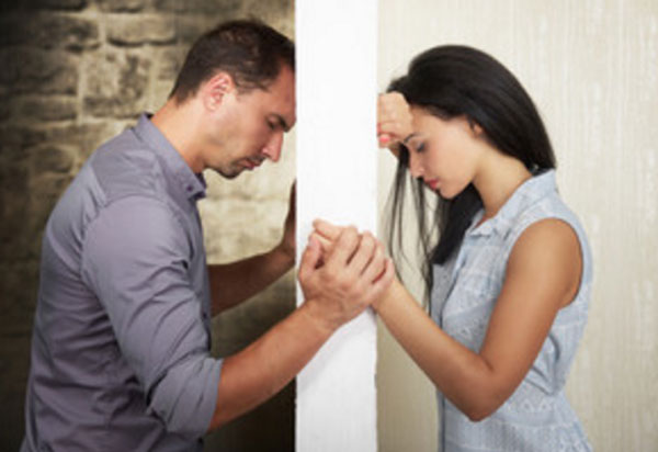 Мужчина и женщина стоят напротив друг друга, их разделяет стена