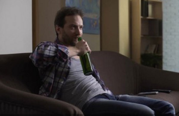 мужик с бутылкой в руках сидит на диване