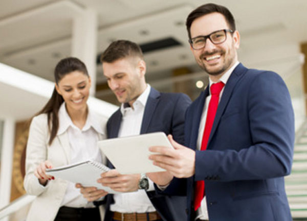 Два коллеги общаются. рядом с ними стоит улыбающийся мужчина