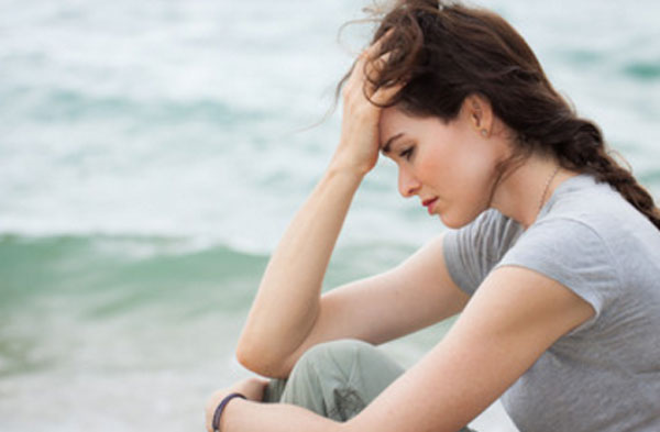 Расстроенная девушка сидит у моря