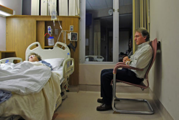 Мужчина сидит возле кровати больной женщины