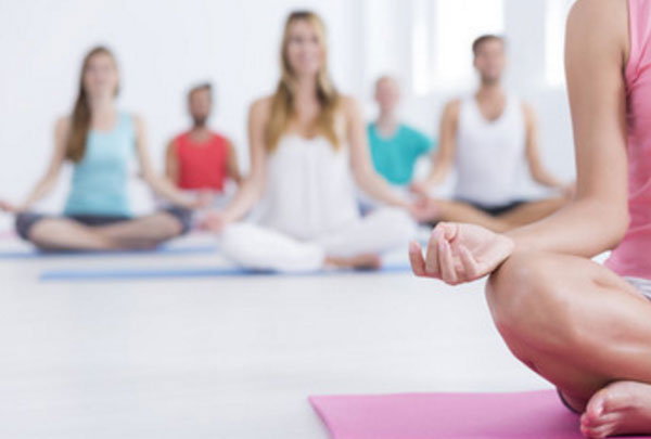 Занятие по медитации. Тренер в розовом и сидит на розовом коврике