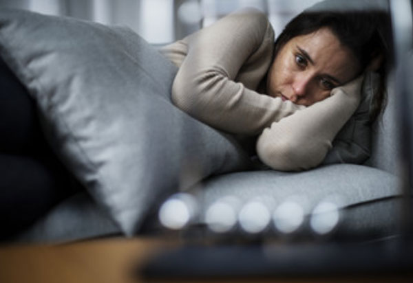 Грустная женщина лежит на диване
