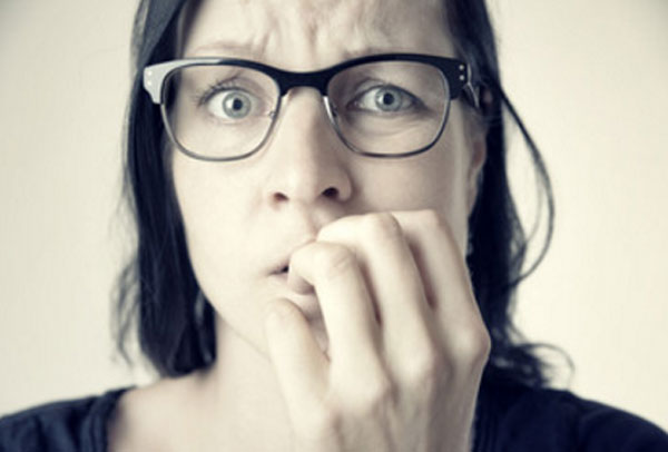 Женщина в очках грызет ногти