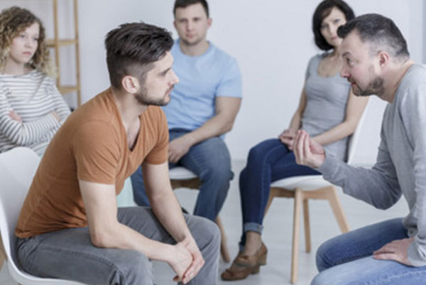 На стульях сидят люди. Напротив друг друга мужчины, один из них что-то доказывает второму