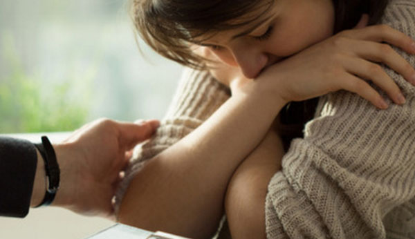 Рука родственника тянется к девушке, у которой депрессия