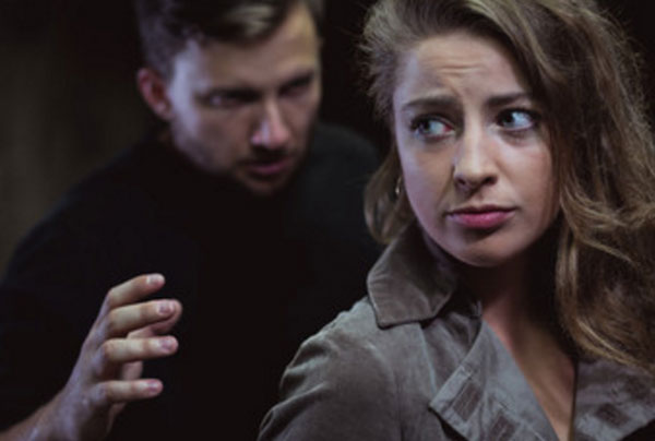 Мужчина стоит сзади слегка испуганной женщины