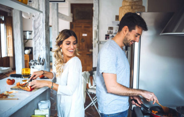 Муж с женой готовят ужин. Она нарезает, а он что-то жарит на сковороде