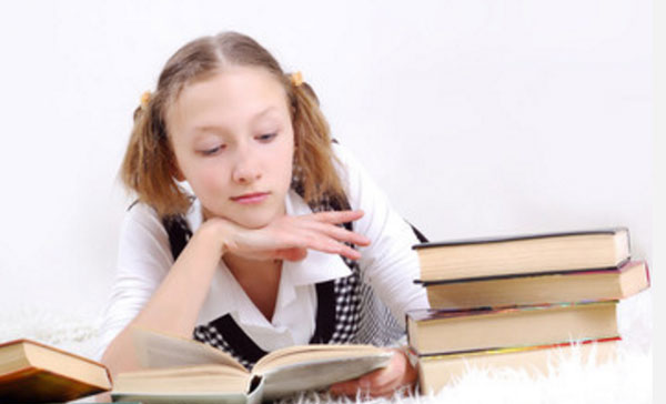 Девушка читает. На столе еще много книг