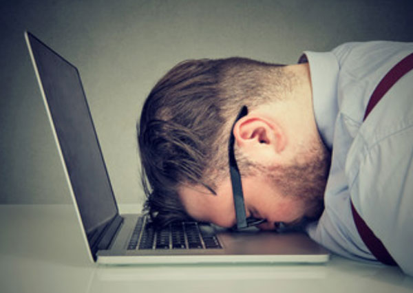 Мужчина в очках положил голову на клавиатуру ноутбука