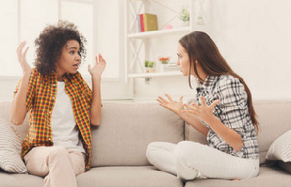 Две девушки беседуют на диване. Одна агрессивно настроена