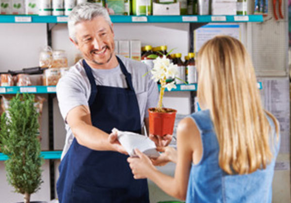 Женщина с продавцом. Она покупает цветок в горшке