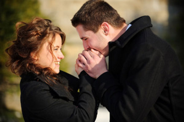 Парень дует на руки девушки, пытается ее согреть