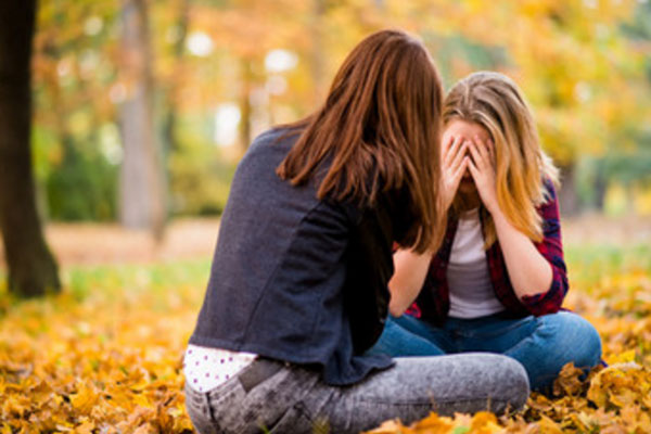 Девушки сидят на осенней листве. Лица прикрыты. сидят друг напротив друга