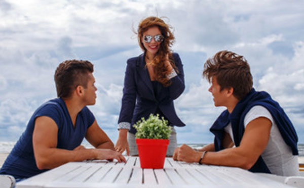 Два парня сидят за столом. К ним подходит девушка