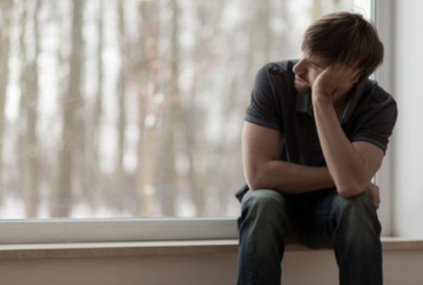 Расстроенный мужчина сидит у окна
