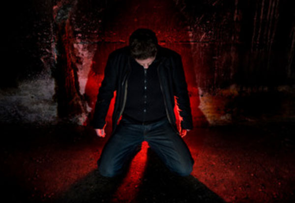 Мужчина стоит на коленях с опущенной головой