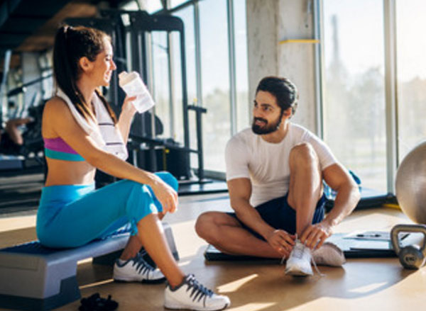 Парень с девушкой в тренажерном зале. Он что-то говорит