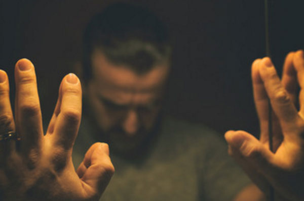 Мужчина стоит перед зеркалом, голову опустил вниз