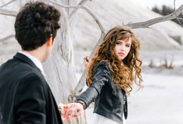 Девушка отдаляется от парня. Он удерживает ее за кончики пальцев