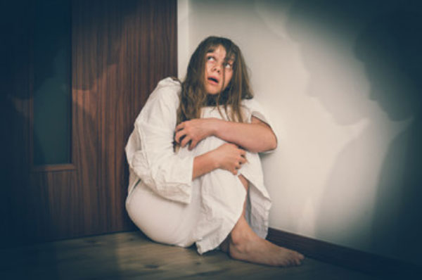 Женщина сидит в углу комнаты. Ей видятся различные тени