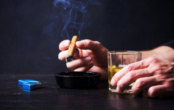 Мужчина курит и держит стакан со спиртным