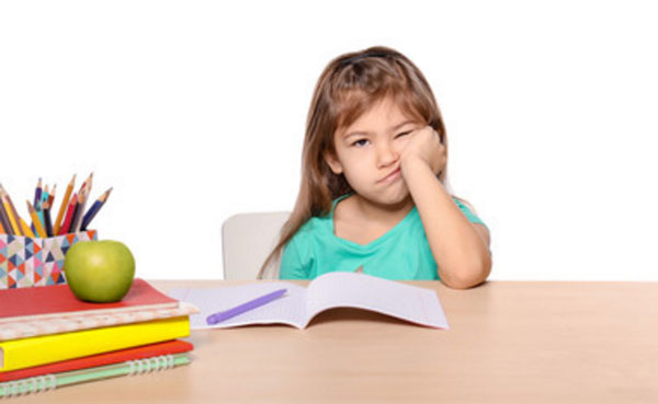 Девочка подпирает голову рукой. Она недовольна. На столе лежат уроки