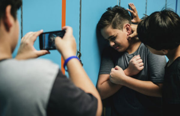 Один парень избивает другого. А третий снимает это на телефон