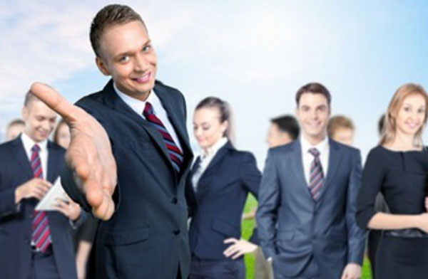 Мужчина в костюме протягивает руку, приглашая к себе. На заднем плане другие люди в костюмах