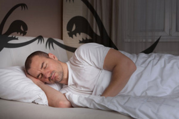 Мужчина спит. На его лице тревога. Сзади него силуэты двух монстров