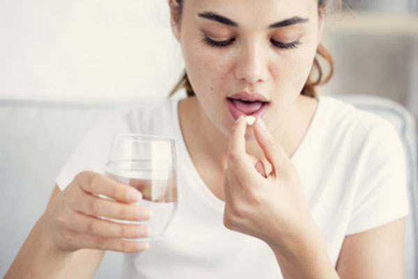 Женщина принимает таблетку