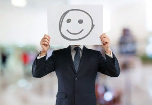 Мужчина в костюме держит перед собой листок бумаги с улыбающейся рожицей