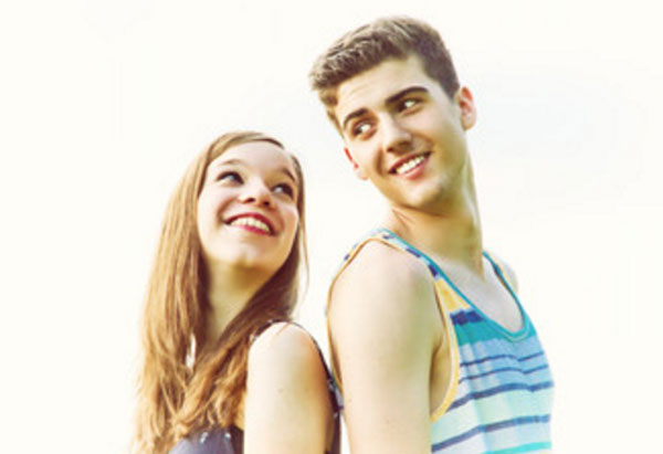 Парень с девушкой стоят друг к другу спиной и смотрят влюбленными глазами