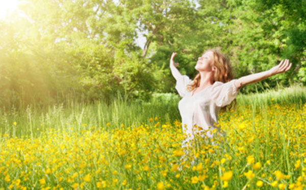 Женщина идет по поляне и радуется солнечным лучам