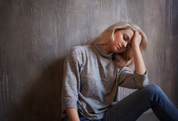 Замученная женщина сидит на полу