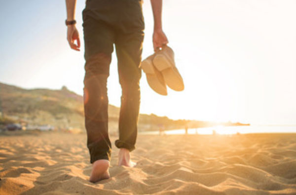 Мужчина идет босиком по песку