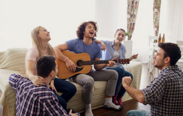 Компания друзей. Душа компании играет на гитаре и поет песню. Все на него смотрят