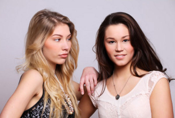 Две девушки стоят вместе, одна завистливо поглядывает