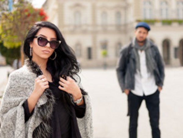 Девушка в пальто, в солнцезащитных очках. Сзади парень