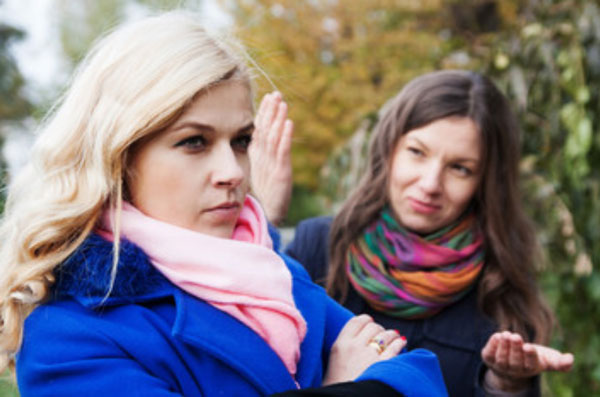 Одна девушка пытается поговорить с другой, а та отворачивается от нее и сердита