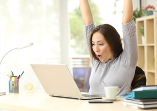 Девушка за ноутбуком чему-то сильно радуется