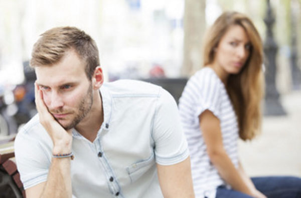 Опечаленный парень. На заднем плане сидит девушка