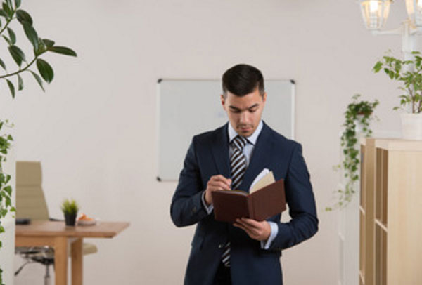 Мужчина в костюме стоит, читая книгу
