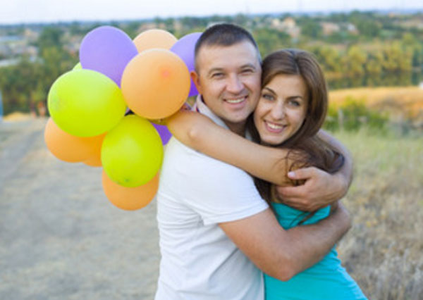 Парень с девушкой обнимают друг друга. Девушка держит шарики