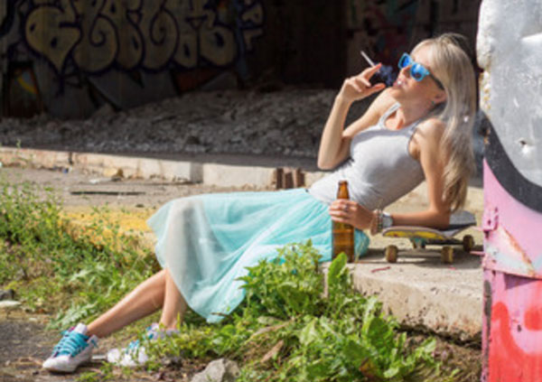 Девушка курит и пьет, облокотившись на бордюр